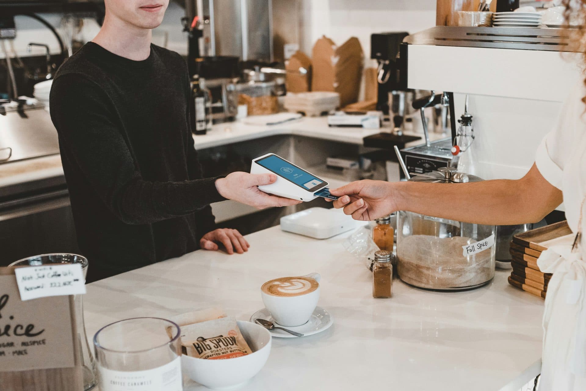 A customer pays by card at a cafe counter